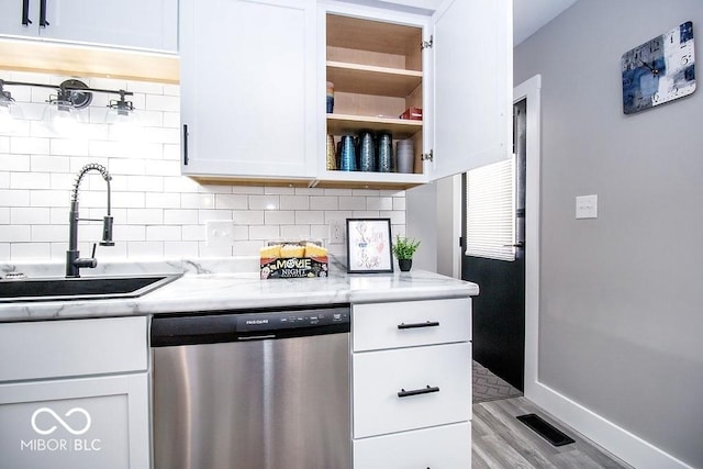 kitchen with a sink, light wood finished floors, tasteful backsplash, stainless steel dishwasher, and visible vents