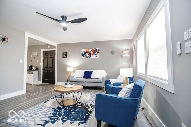 living room with baseboards, a ceiling fan, and wood finished floors
