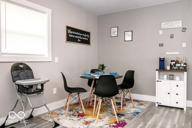 dining area with baseboards and wood finished floors