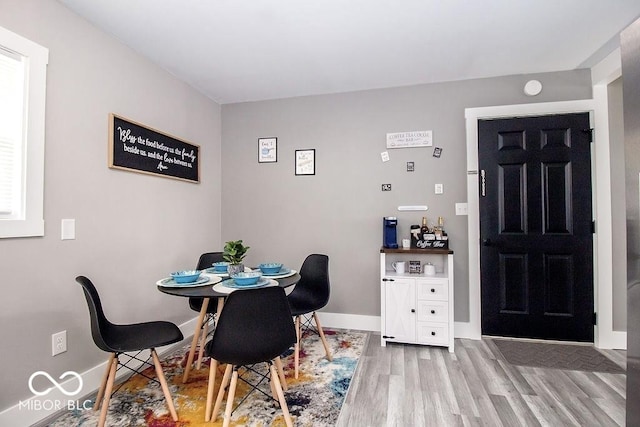 dining area featuring baseboards and light wood-type flooring