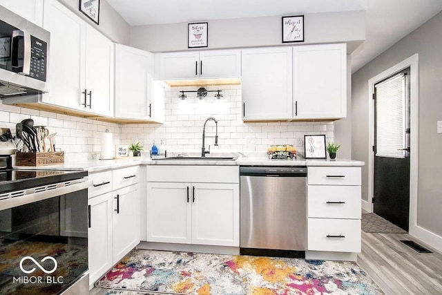 kitchen featuring visible vents, light countertops, a sink, light wood finished floors, and stainless steel appliances