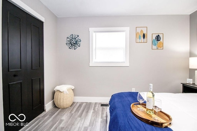 bedroom with baseboards, wood finished floors, and visible vents