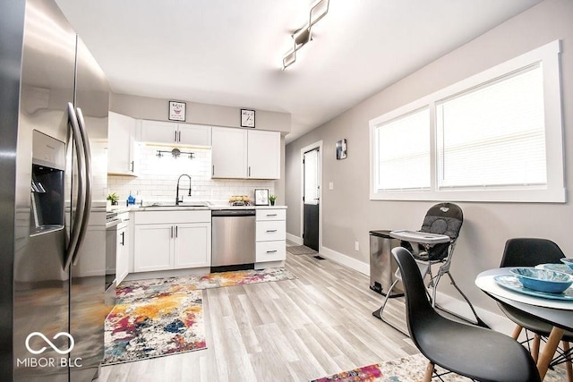 kitchen featuring a sink, appliances with stainless steel finishes, tasteful backsplash, and white cabinetry
