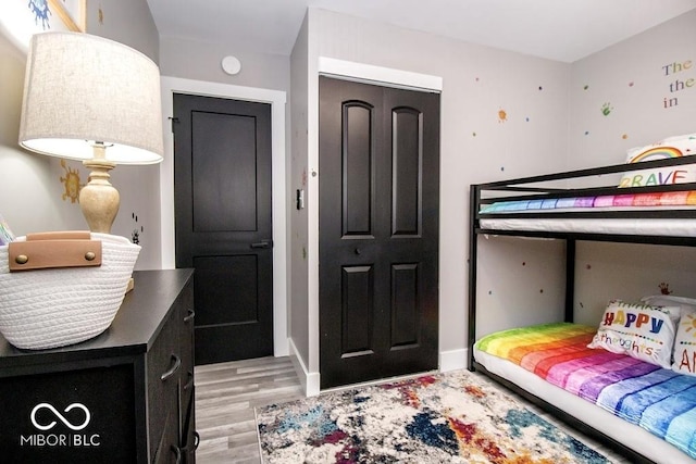 bedroom with baseboards, light wood-style flooring, and a closet