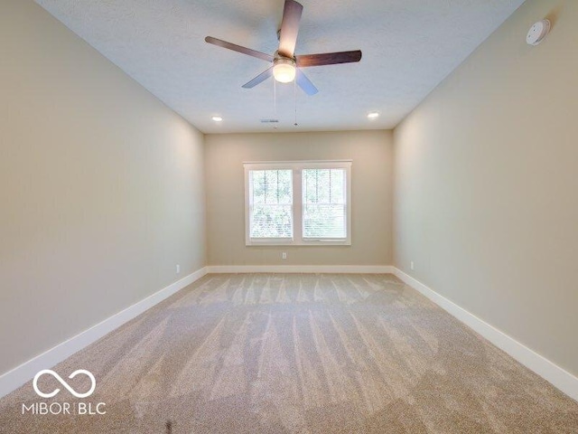 spare room featuring baseboards, light carpet, and a ceiling fan