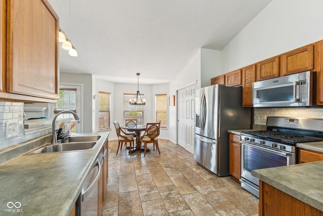 kitchen with decorative backsplash, stone finish floor, brown cabinets, a sink, and appliances with stainless steel finishes