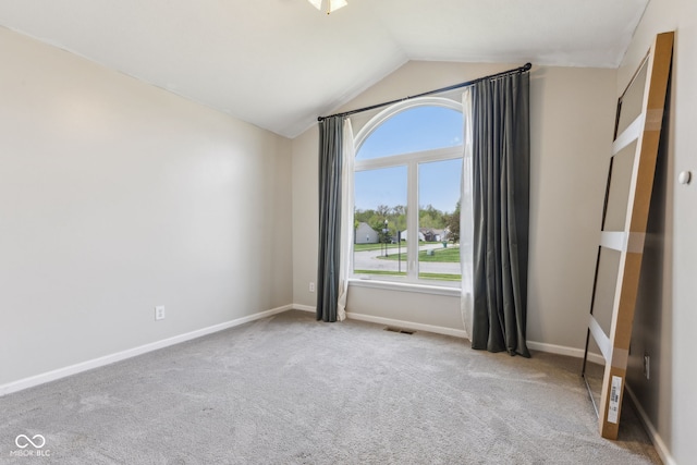 empty room with carpet flooring, baseboards, visible vents, and lofted ceiling