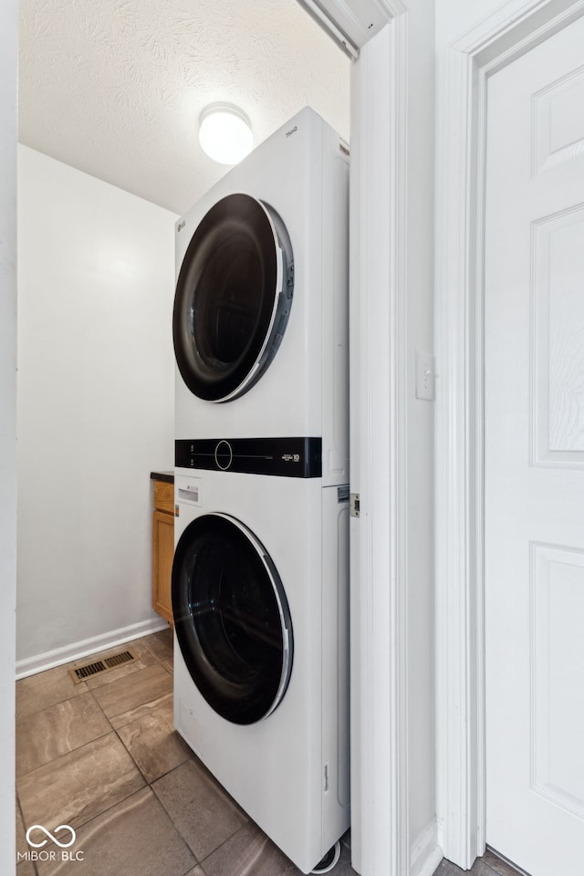 washroom featuring baseboards, stacked washer / drying machine, laundry area, and visible vents