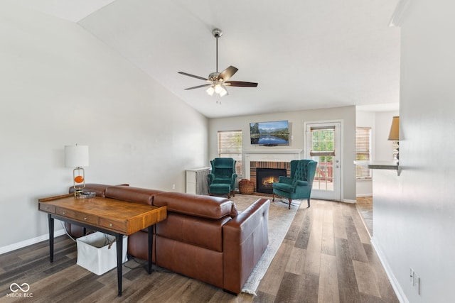 living area with ceiling fan, a brick fireplace, high vaulted ceiling, baseboards, and wood finished floors