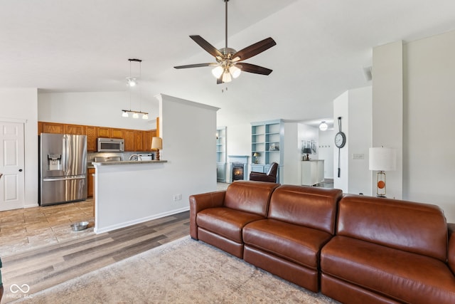 living area with light wood-style floors, high vaulted ceiling, and a ceiling fan