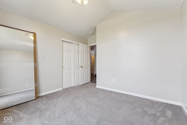 unfurnished bedroom featuring baseboards, carpet flooring, and lofted ceiling