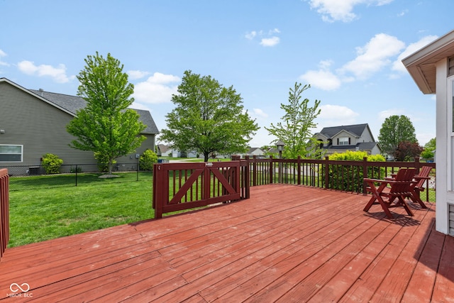 wooden deck with a lawn, fence, and a residential view