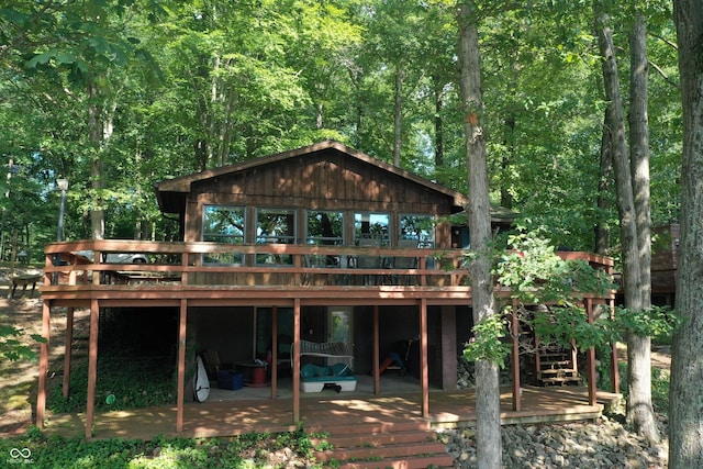 back of house with a wooden deck and a forest view