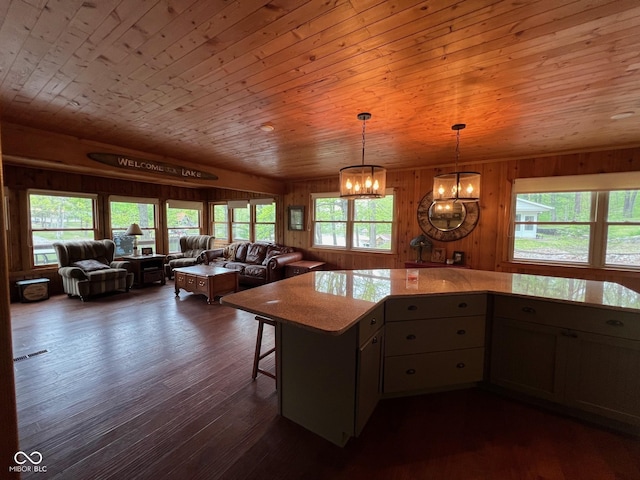 kitchen featuring an inviting chandelier, light countertops, wood walls, open floor plan, and dark wood-style floors