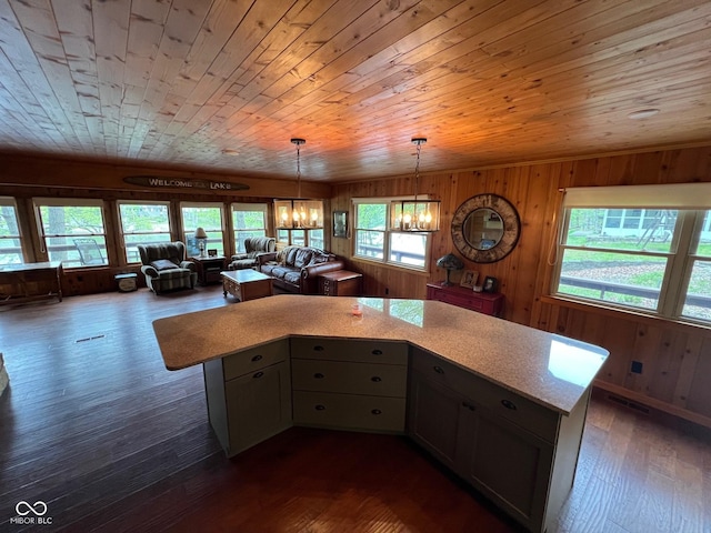 kitchen with decorative light fixtures, wood walls, light countertops, a notable chandelier, and dark wood-type flooring