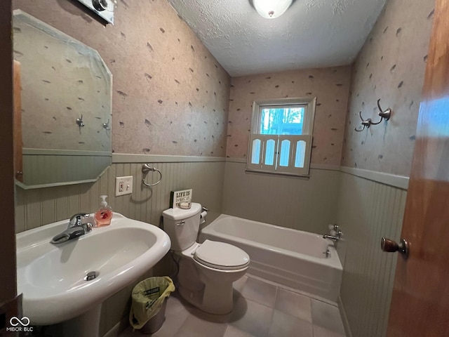 full bathroom with toilet, wainscoting, a sink, and a bath