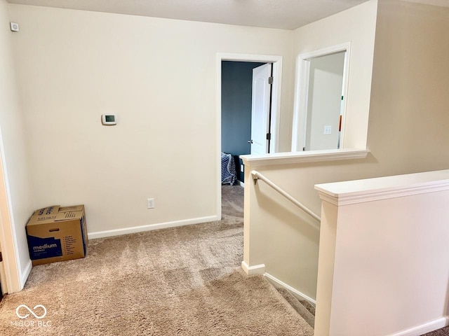 hall with baseboards, carpet flooring, and an upstairs landing