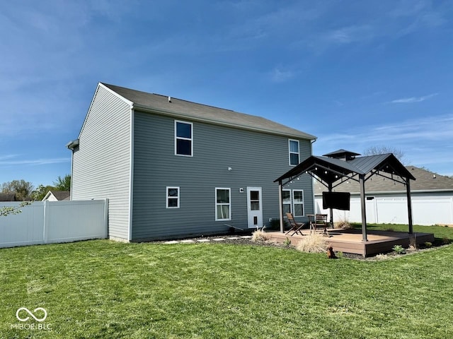 rear view of property with a yard, a gazebo, and fence