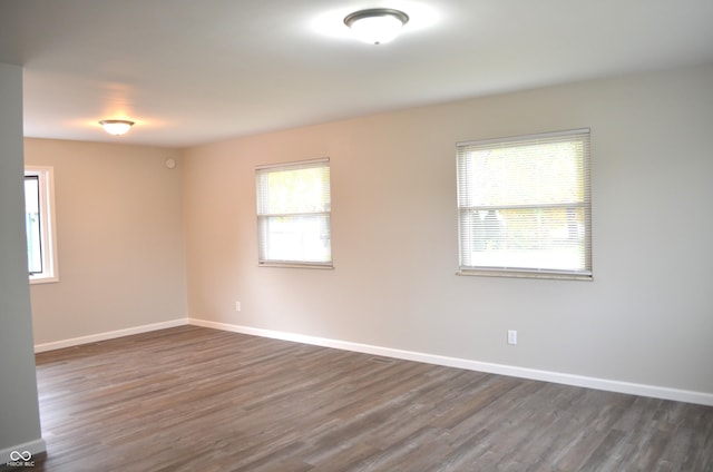 unfurnished room featuring baseboards and dark wood-style flooring