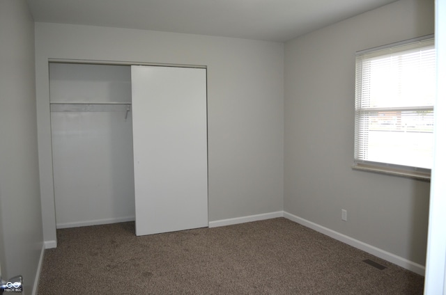 unfurnished bedroom with carpet flooring, baseboards, and a closet