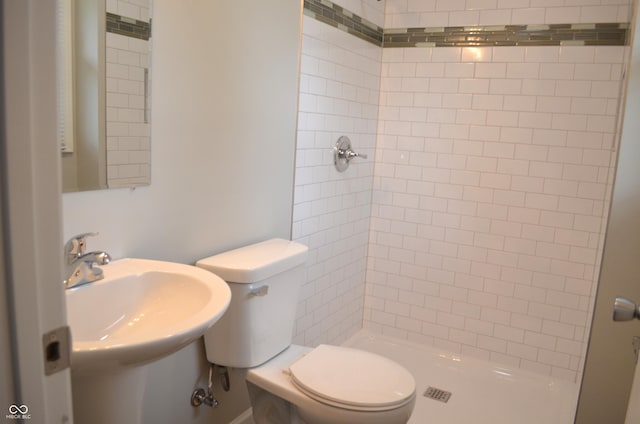 bathroom featuring a sink, a shower stall, and toilet