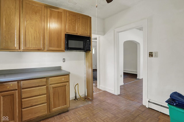 kitchen with black microwave, arched walkways, ceiling fan, and baseboard heating