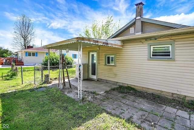 rear view of house with a lawn, fence, a chimney, and a patio area