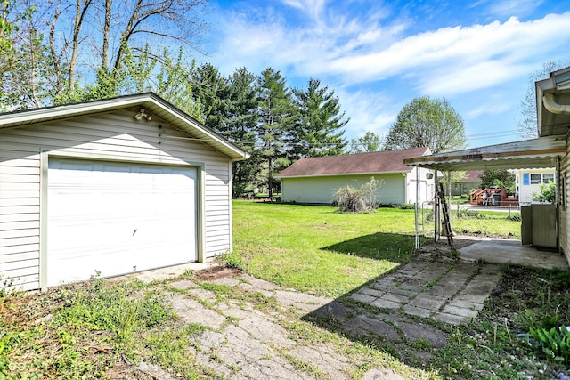 view of yard with an outdoor structure, driveway, and a detached garage