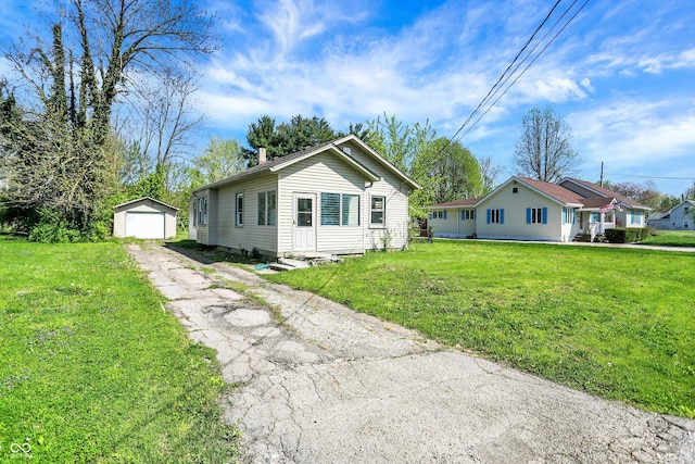 bungalow-style home with a detached garage, an outbuilding, a front lawn, and aphalt driveway