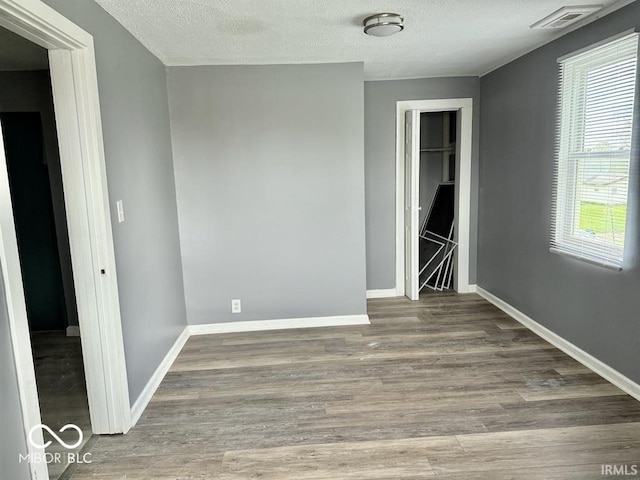 unfurnished bedroom with baseboards, visible vents, and wood finished floors