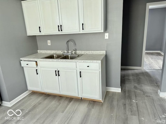 kitchen with light wood-style floors, a sink, and baseboards