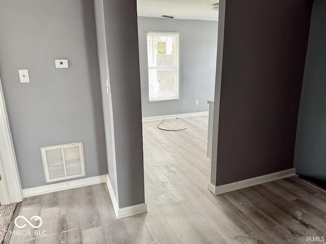 corridor with visible vents, baseboards, and wood finished floors
