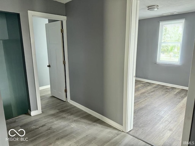 hall with baseboards, visible vents, and wood finished floors