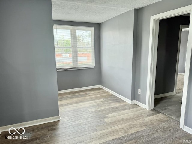 interior space with baseboards, a textured ceiling, and wood finished floors