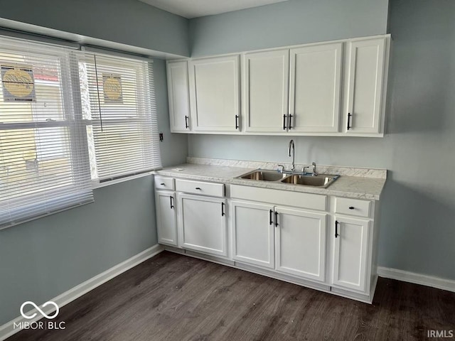 kitchen with a sink, baseboards, white cabinets, and dark wood-style floors