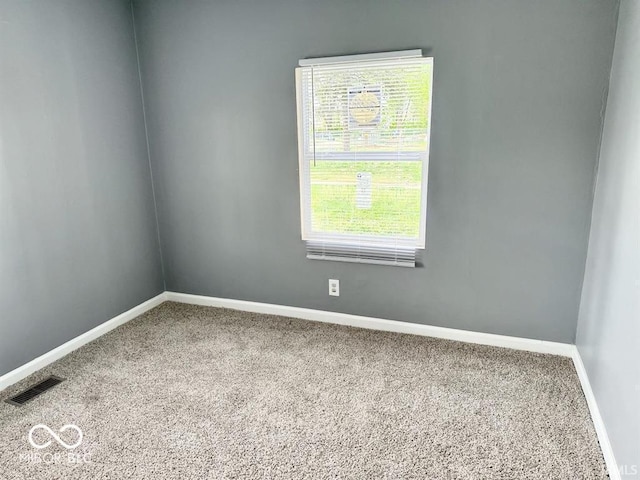 unfurnished room featuring baseboards, visible vents, and carpet