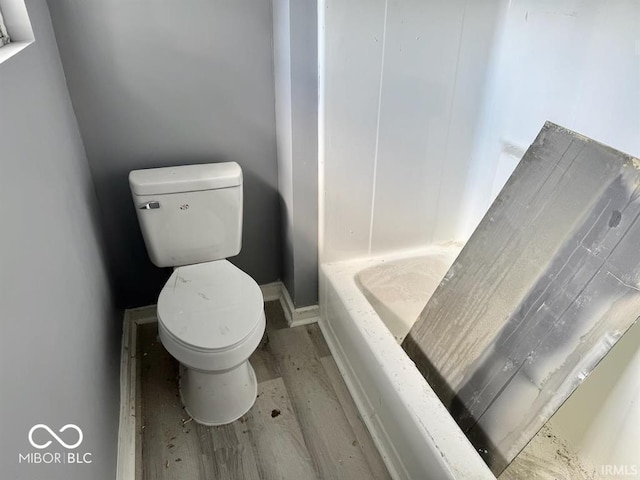 full bathroom with a tub, toilet, and wood finished floors