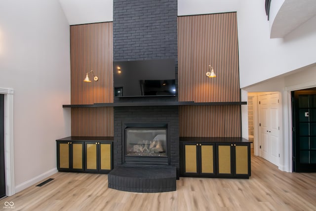12520 E Stanley Rd, Selma, IN 47383 - living area with a fireplace, baseboards, wood finished floors, a towering ceiling, and visible vents