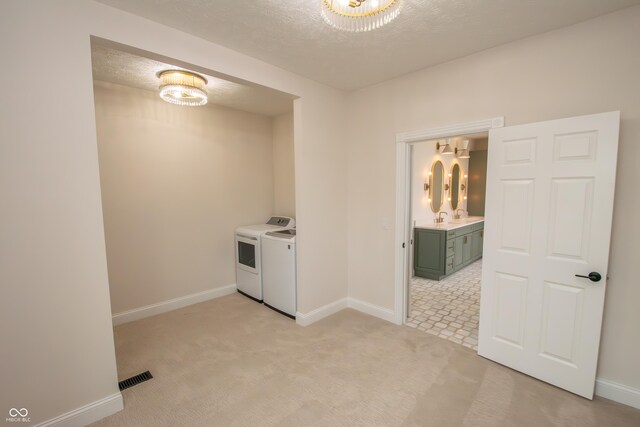 12520 E Stanley Rd, Selma, IN 47383 - washroom with a textured ceiling, baseboards, an inviting chandelier, separate washer and dryer, and light carpet