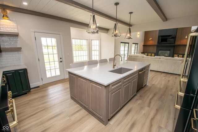12520 E Stanley Rd, Selma, IN 47383 - kitchen with stainless steel dishwasher, a sink, light countertops, beamed ceiling, and light wood-style floors