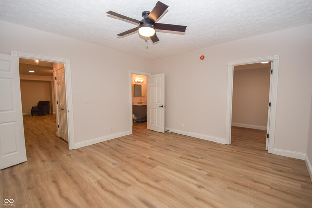 12520 E Stanley Rd, Selma, IN 47383 - unfurnished bedroom with baseboards, a textured ceiling, light wood-style flooring, and a walk in closet