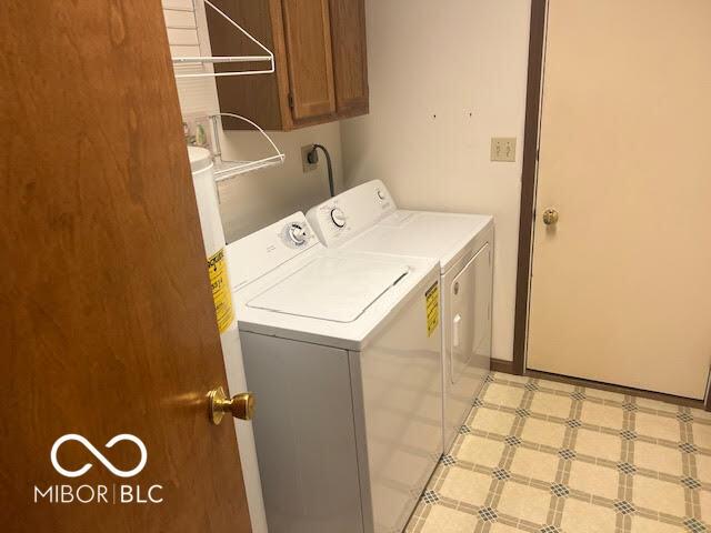 washroom with light floors, cabinet space, and washing machine and clothes dryer