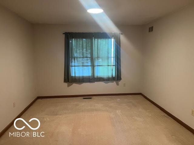 empty room with baseboards, light colored carpet, and visible vents