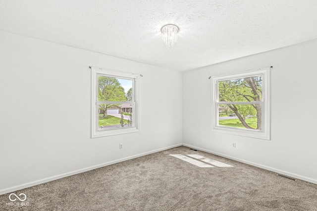 carpeted spare room featuring baseboards, a textured ceiling, and visible vents