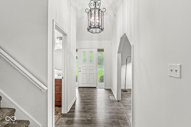foyer entrance with visible vents, arched walkways, wood finished floors, a chandelier, and stairs