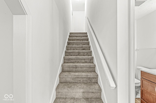 stairway featuring baseboards and carpet