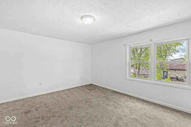 carpeted spare room featuring a textured ceiling, visible vents, and baseboards