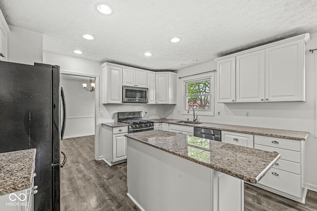 kitchen featuring dark wood-type flooring, a sink, appliances with stainless steel finishes, and white cabinets