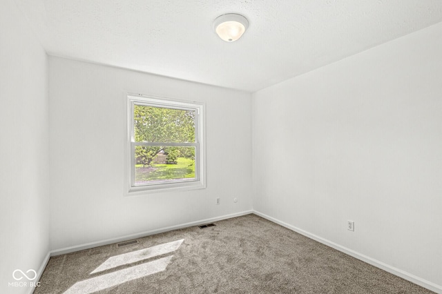 spare room with carpet flooring, baseboards, and visible vents