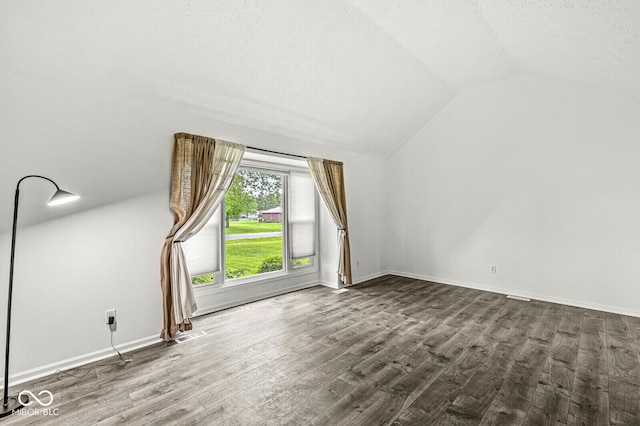 additional living space with baseboards, vaulted ceiling, and wood finished floors